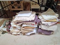 two stacks of folded table linens in assorted colors and styles with tassel cords left side