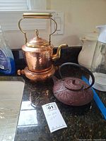 Copper kettle and cast iron teapot side by side on countertop