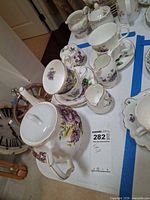 Entire porcelain floral tea set showing teapot, sugar bowl, creamer, stacked teacups and saucers