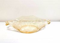 Side profile of amber and clear depression glass bowl showing handles and etched pattern
