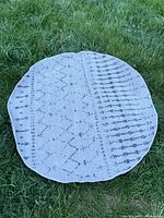 Full view of round gray geometric rug on grass