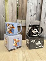 Both mugs stacked on their respective boxes showing front graphics