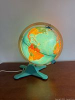 Globe illuminated, showing Africa and Atlantic regions on teal base