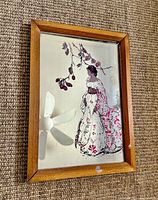Framed wall mirror showing illustration detail and wood frame