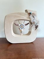 Front view of ceramic frame vase with skull and feathers