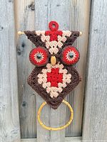 Front view of crocheted owl towel holder against wood fence