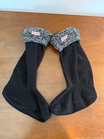 Full view pair of boot liners laid flat showing black fleece body and gray knit cuff