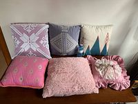 Six pillows on table showing variety of designs and colors