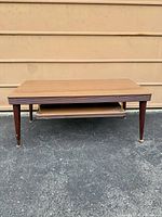 Full front view showing table top, shelf, tapered legs, brass foot glides