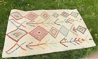 Full view of wool rug showing overall pattern and size reference on grass