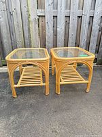 Pair of rattan side tables with glass tops and slatted lower shelves