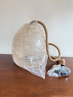 Pendant light with plastic wrap showing shade, rope cord and hardware bag
