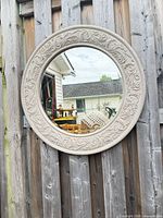 front view of round ornate mirror on fence