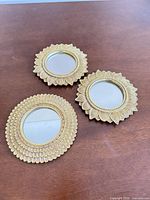 Three gold floral wall mirrors on table