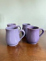 Front angled view of four purple ceramic mugs