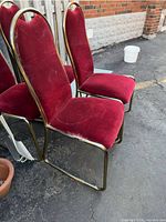 Side view of two chairs showing brass-tone frame and red velvet fabric