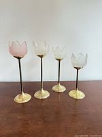 Front view of four brass and glass tulip candle holders