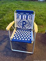 Front view of aluminum lawn chair showing blue and white woven FLT and R design, wooden armrests