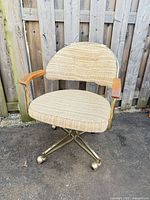 Front view of brass-finish swivel office chair showing upholstered seat/back and wooden armrests