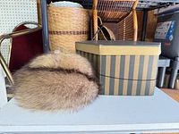 Fox fur hat beside striped hat box