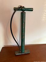 Full view of green floor pump standing upright showing handle, hose and base