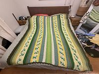 Full view of crocheted afghan spread on queen bed showing overall size and striped floral pattern