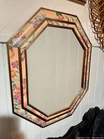 Front view of octagonal mirror with floral painted frame and gold trim