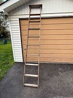 Full view of ladder leaning against garage showing overall length and structure