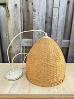 Side view of woven wicker pendant lamp with canopy and cord visible