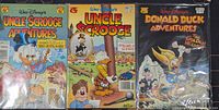 Front covers of three Walt Disney comic books in sleeves