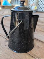 Black speckled enamelware kettle showing lid, spout, handle