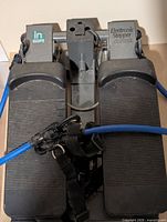 Top view showing both foot pedals, central console mount, and attached blue resistance tubing