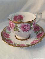 Teacup on saucer showing rose pattern and gold trim