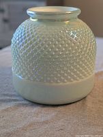 Front view of iridescent teal hobnail glass vase showing texture and color