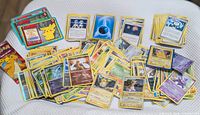Spread of loose Pokémon cards displaying variety of types, trainers and promos