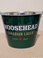 Front view Moosehead Canadian Lager green metal bucket with handle