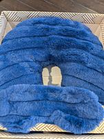 Top view of blue plush U-shaped travel neck pillow in box
