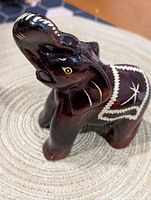 Full view of carved wooden elephant figurine showing raised trunk and white decorative etching