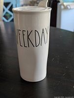 Front view of white ceramic travel mug with "WEEKDAY" text and lid attached