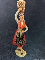 Full view of porcelain figurine showing costume, basket, and base