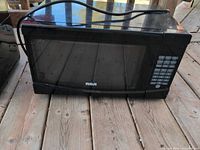 Front view of black RCA microwave showing door and control panel