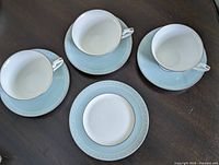 Three cups on saucers plus side plate overhead view