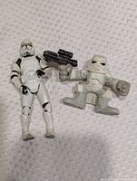 Front view of Clone Trooper and Snowtrooper figures side by side on textured surface