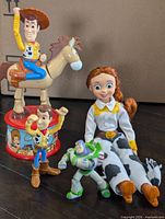 Group of four Toy Story toys: Woody on Bullseye figure, small Woody, Jessie doll, Buzz Lightyear figure