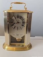 Front view of Bulova gold-tone carriage clock showing full case, handle and base