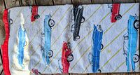 Folded blanket showing car pattern and red satin binding