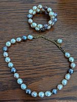 Full view of necklace and bracelet set laid flat on wood surface