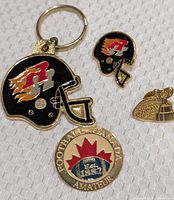 All four items: helmet keychain, helmet pin, Grey Cup trophy pin, Football Canada Amateur pin