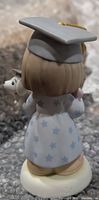Back view of Precious Moments graduation figurine showing star-patterned gown, mortarboard, dog companion
