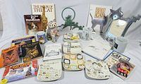 Full lot overview showing books, plates, mugs, figurine, metal décor